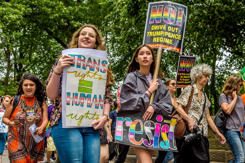 Protesters hold up signs saying things like, "Resist," and "Trans rights = human rights."